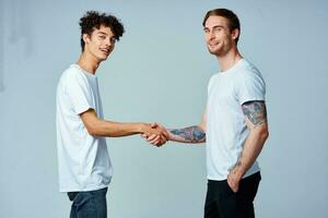 dos amigos sostener manos en blanco camisetas aislado antecedentes foto