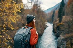 woman hiker with a backpack on her back near a mountain river in nature, back view photo