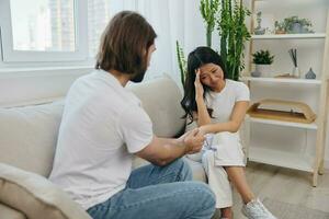 An Asian woman is sad and crying with her male friend at home. Stress and misunderstanding in a relationship between two people photo