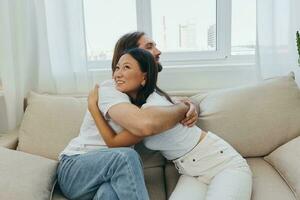 A man and a woman are sitting on the couch at home wearing white T-shirts and hugging each other with smiles. Family life lifestyles of young marrieds photo