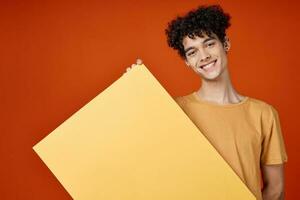 guy with curly hair yellow poster in hands studio advertising Copy Space photo