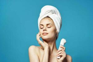 beautiful woman with a towel on her head massager in hands skin care photo