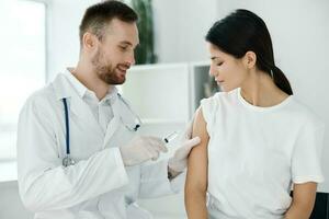 doctor in hospital giving injection to female patient vaccine protective gloves photo