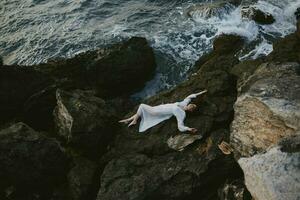 beautiful young woman lying on rocky coast with cracks on rocky surface Summer vacation concept photo