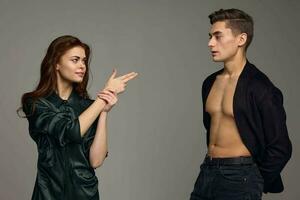 Sexy man in a jacket and a woman gesturing with her hands on a gray background photo