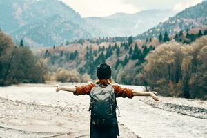 woman tourist with raised hands hangars on nature in autumn near the river photo