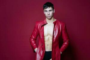 male athlete brunette in a leather coat on a red background photo