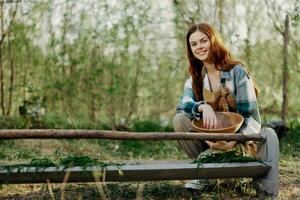 mujer granjero sonrisas y vierte comida para el aves a el pájaro alimentador a el pollo granja foto