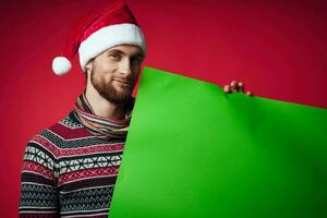 handsome man in a santa hat holding a banner holiday red background photo