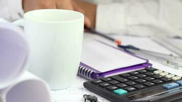 Focused man calculate to project plan cost and write data in notebook, businessman working in architecture office with coffee, selective focus video