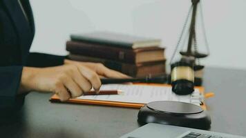 Business and lawyers discussing contract papers with brass scale on desk in office. Law, legal services, advice, justice and law concept picture with film grain effect video