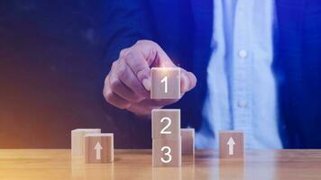 Businessman hand puts a wooden block with the number one on top of the tiered cubes. First step, Level or Ranking and Business competition concept. photo