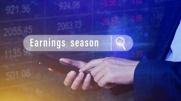 Earnings season, Hand touching of written in search bar with the financial data visible on background with smartphone,  Reports Stock Market Ticker Words photo