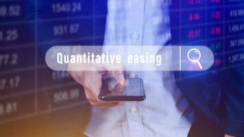 Quantitative easing written in search bar on smartphone with the financial data visible on background, Quantitative easing concept stock Market online marketing photo