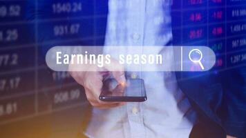 Earnings season, Hand touching of written in search bar with the financial data visible on background with smartphone,  Reports Stock Market Ticker Words photo
