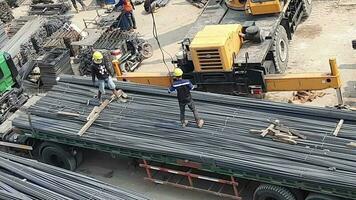 Jakarta, Indonesia in March 2023. Several construction workers who are blacksmiths are unloading iron from the trailer. Lowering of iron is assisted by using a service crane. video