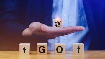 Concept of business planning strategy, Hand choose the wooden cube block with icon aiming goal Action plan and words GO, success and business target concept, company strategy development. photo