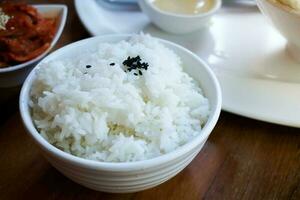 Rice in white cup on wood background and black sesame photo