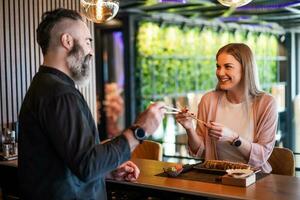 Sushi master showing a woman how to use chopsticks. photo