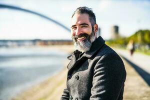 Happy businessman is sitting outdoor in the city and enjoying sun in autumn. photo