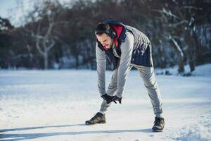 Adult man is stretching in the park in wintertime. photo