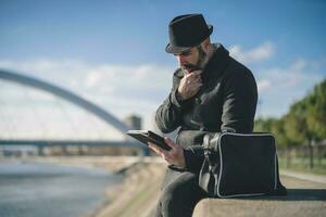 Man is sitting outdoor in the city and using digital tablet. photo