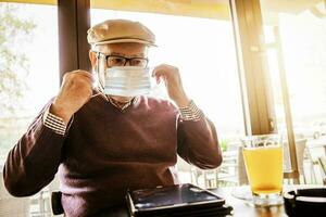 Old man with face mask at a coffee shop photo