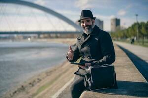 hombre es sentado al aire libre en el ciudad y utilizando digital tableta. foto