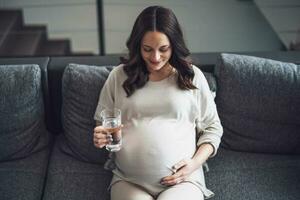 Pregnant woman drinking water at home. photo