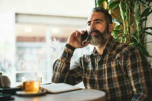 Adult man is sitting in cafe on the phone photo