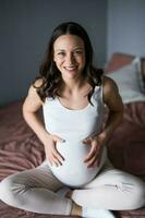 Pregnant woman with hands on her belly at home photo