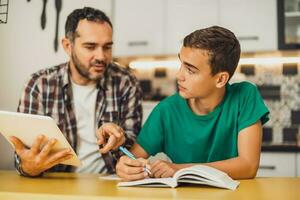 Father is helping his son with learning. They are doing homework together. photo