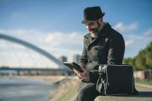 Man is sitting outdoor in the city and using digital tablet. photo