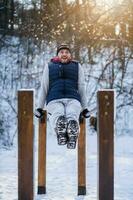 Adult man is exercising on push-up bar in park in wintertime. photo