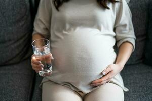 Pregnant woman drinking water at home. photo