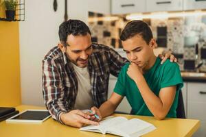 Father is helping his son with learning. They are doing homework together. photo