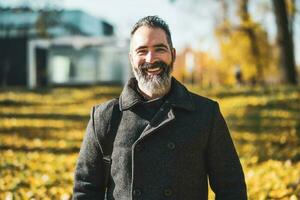 Businessman is in front of company building in park. Happy businessman in autumn. photo