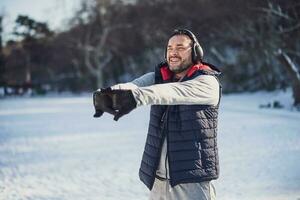 Adult man is stretching in the park in wintertime. photo