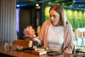 joven mujer comiendo japonés comida con palillos foto