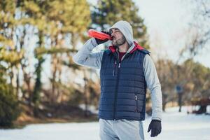 Adult man is exercising on the park in wintertime. photo