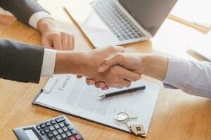 Close up hand of asian young male new landlord, tenant or rental handshake with home, apartment agent or realtor man after bank approved mortgage, loan signed purchase contract. Property of financial. photo