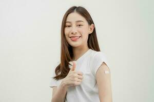 Portrait of pretty, beautiful asian young, teenage attractive after getting, receive anti virus vaccine covid-19. Showing arm on white bandage isolated on white background, copy space. photo
