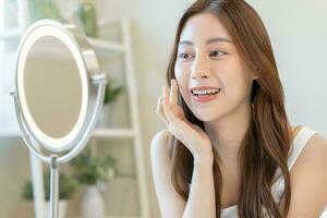 Fresh, nice healthy skin, beautiful of asian young woman, girl looking at mirror, touching her face with before make up cosmetic routine at home. Female look with natural fashion style, Facial Beauty. photo