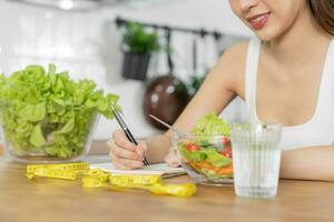 dieta, dieta asiático joven mujer laboral, escribir dieta plan Derecha nutrición, vegetales ensalada es comida para bueno salud no escoger comer basura alimento. nutricionista femenino, peso pérdida persona. foto