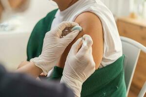 Covid-19,coronavirus, elderly asian adult woman getting vaccine from doctor or nurse giving shot to mature patient at clinic. Healthcare, immunization, disease prevention against flu or virus pandemic photo