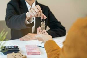 Asian agent giving a key to new owner or tenant, client after signed signature contract rental purchase, buyer apartment, home with landlord, realtor. Banker agreement mortgage loan. Property lease. photo