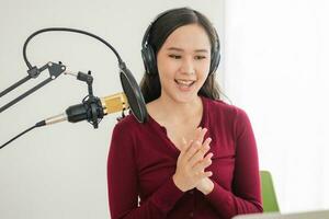 hermosa joven presentadora de radio asiática trabajando, poniendo micrófono, preparándose para hablar antes de grabar podcast y vivir en las redes sociales. tecnología de transmisión en línea en el aire en el estudio doméstico. foto