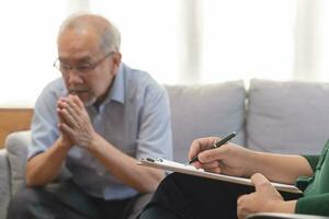 Psychology, depression people. Elderly asian adult man, men consulting with psychologist ,psychiatrist while elderly, old patient counseling mental with doctor woman at clinic. Encouraging, therapy. photo