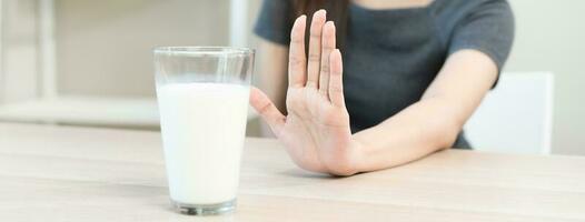 alergia asiático joven mujer, niña mano en denegar, No o empujar fuera a evitar para bebida Leche a hogar, infeliz y malo estómago dolor. lactosa intolerancia y lechería alimento, salud problema, barriga sufrir concepto. foto