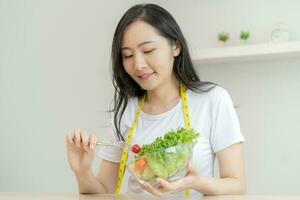 dieta, dieta asiático joven mujer o niña utilizar tenedor a tomate en mezcla verduras, verde ensalada bol, comer comida es bajo grasa bueno salud. nutricionista femenino, peso pérdida para sano persona. foto